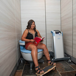 Female patient sitting on Emsella chair reading a book at Chinn GYN