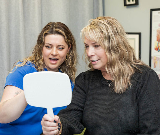 Two woman looking into mirror going over IPL Photofacial results.